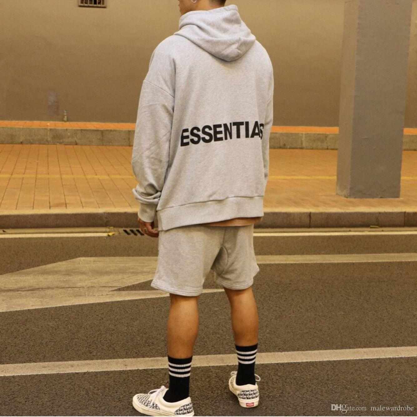 Pria menggunakan hoodie bertulisan essentials dengan short pants dan sneakers